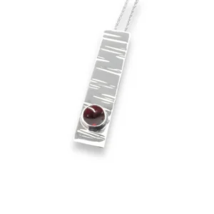 Sterling silver and 5mm Garnet pendant featuring the bark texture. This pendant comes complete with a 16-18″ sterling silver chain.