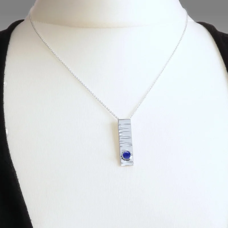 Sterling silver and 5mm Lapis Lazuli pendant featuring the bark texture. This pendant comes complete with a 16-18″ sterling silver chain.