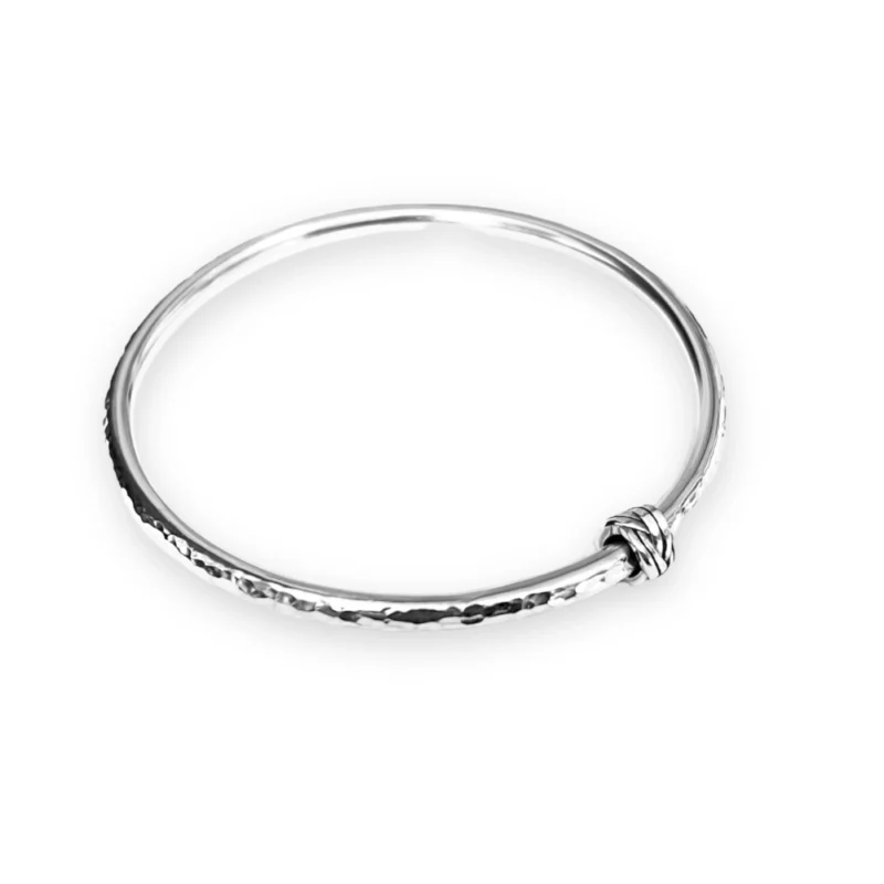 Sterling silver bangle with dimple texture and sterling silver celtic knot charm. Available in 4 sizes.