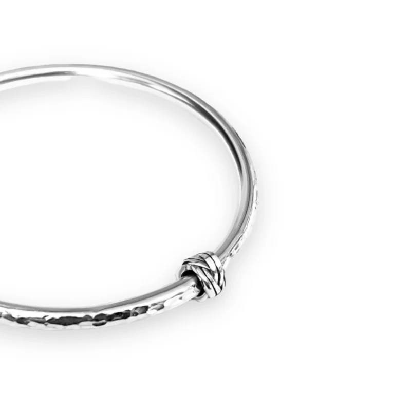 Sterling silver bangle with dimple texture and sterling silver celtic knot charm. Available in 4 sizes.