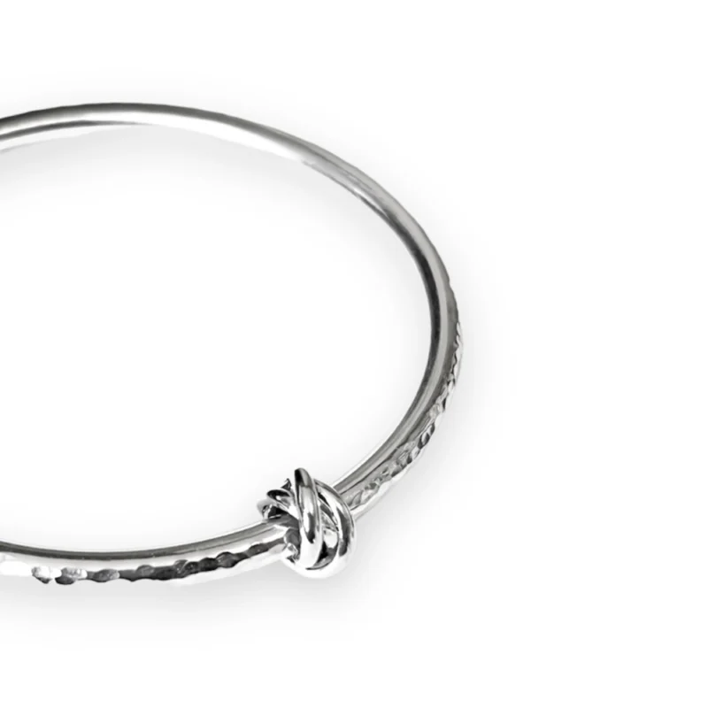 Sterling silver bangle with dimple texture and sterling silver russian knot charm. Available in 4 sizes.